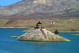 View of Hanna Lake in Quetta with turquoise water surrounded by mountains and trees under a clear blue sky.
