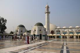 Khari Sharif Shrine with intricate architecture and devotees offering prayers under blue skies.