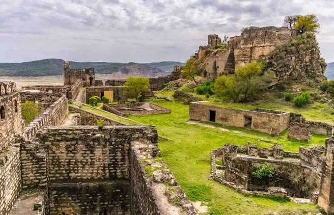 Stone walls and towers of Ramkot Fort overlooking the blue waters of Mangla Lake.