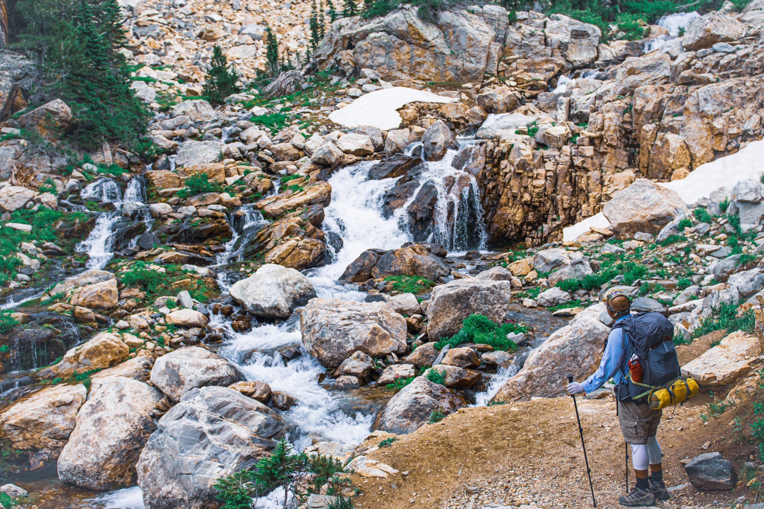 A high angle shot of a hiker admiring the small brook on the stones