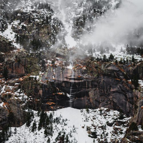 High waterfall on a cliff in the mountains with snow in winter